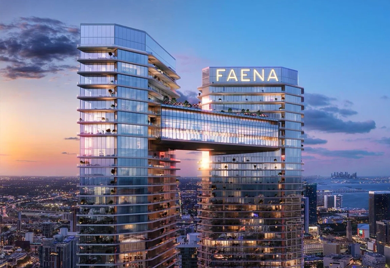 Faena Residences luxury towers in Miami at sunset, with modern architectural design, palm trees and river view.